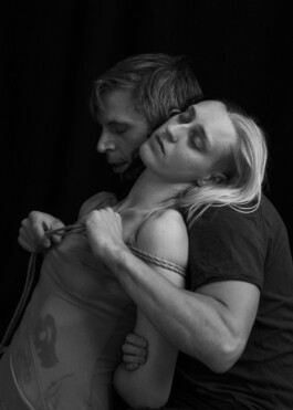 Black and white photo of Iris Red Horse tying a woman, relaxed body language 