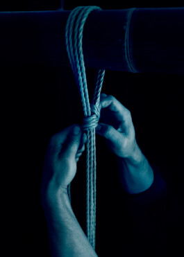 Hand preparing a shibari rope line over bamboo. Calm, controlled and safe rope practice built on trust and attention.